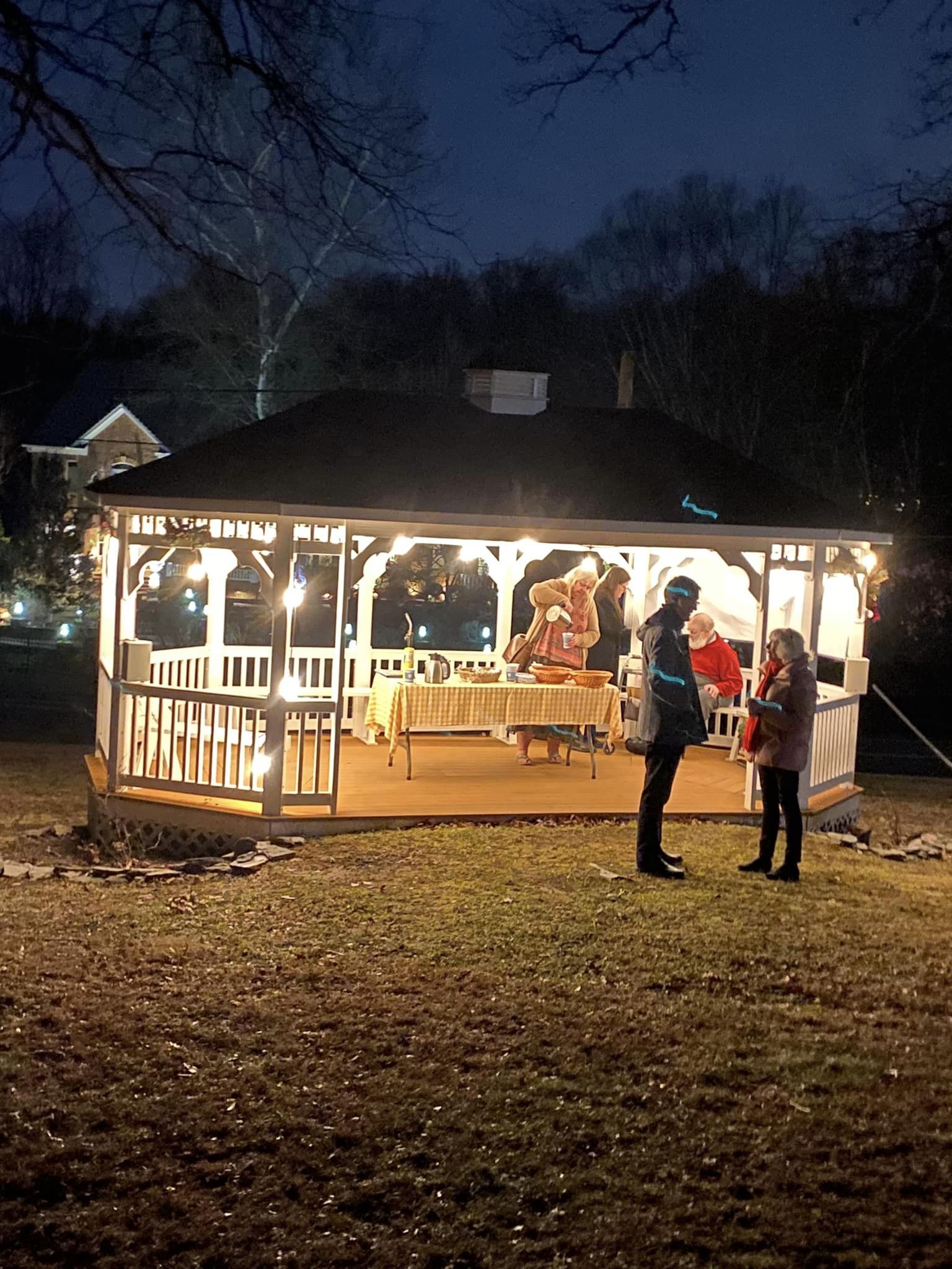 people standing at a gazebo at night with lights