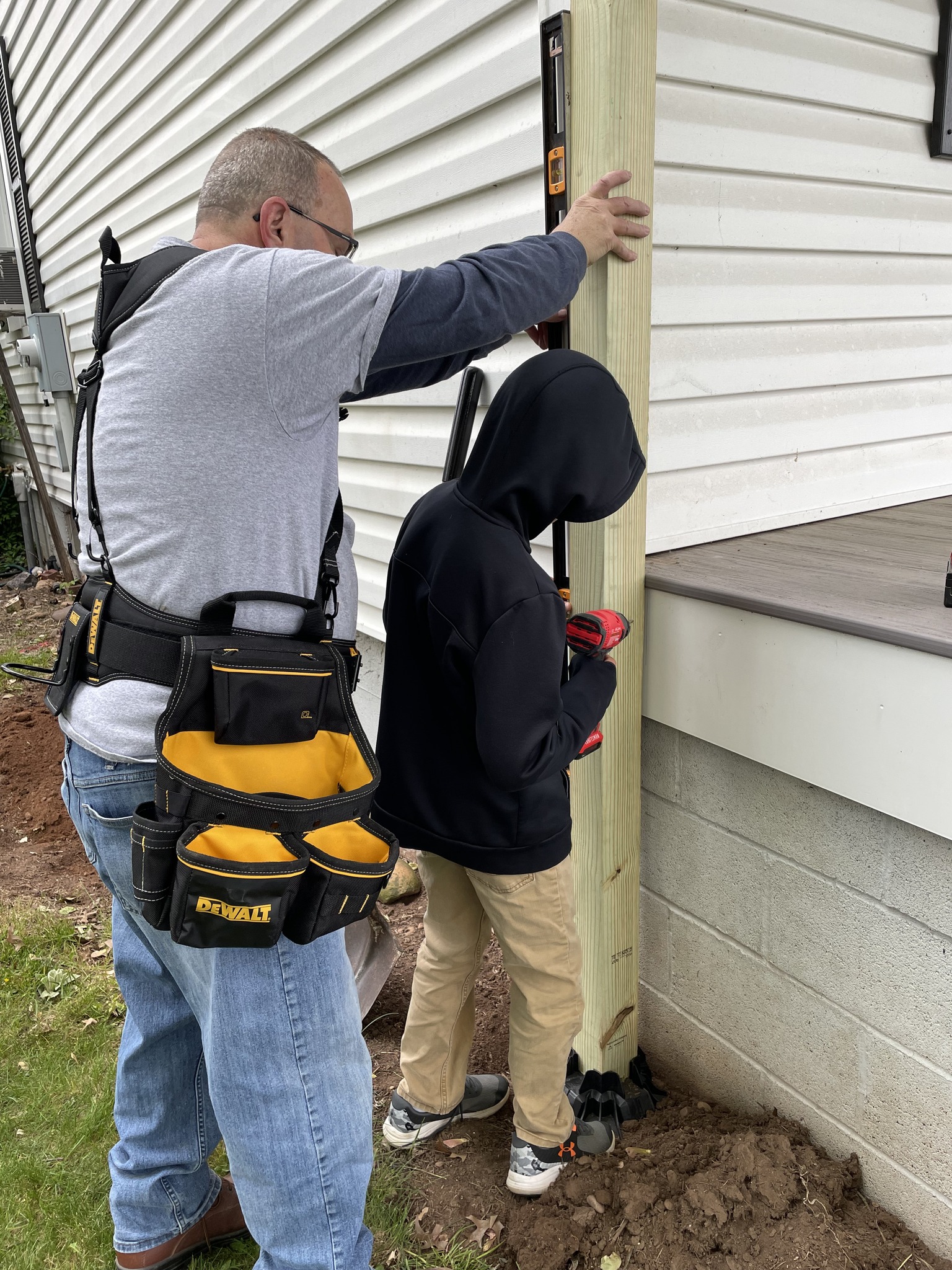 man helping a boy screw in a post