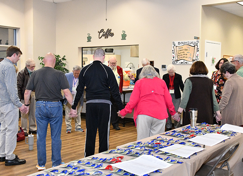 Group holding hands in a circling praying before an event