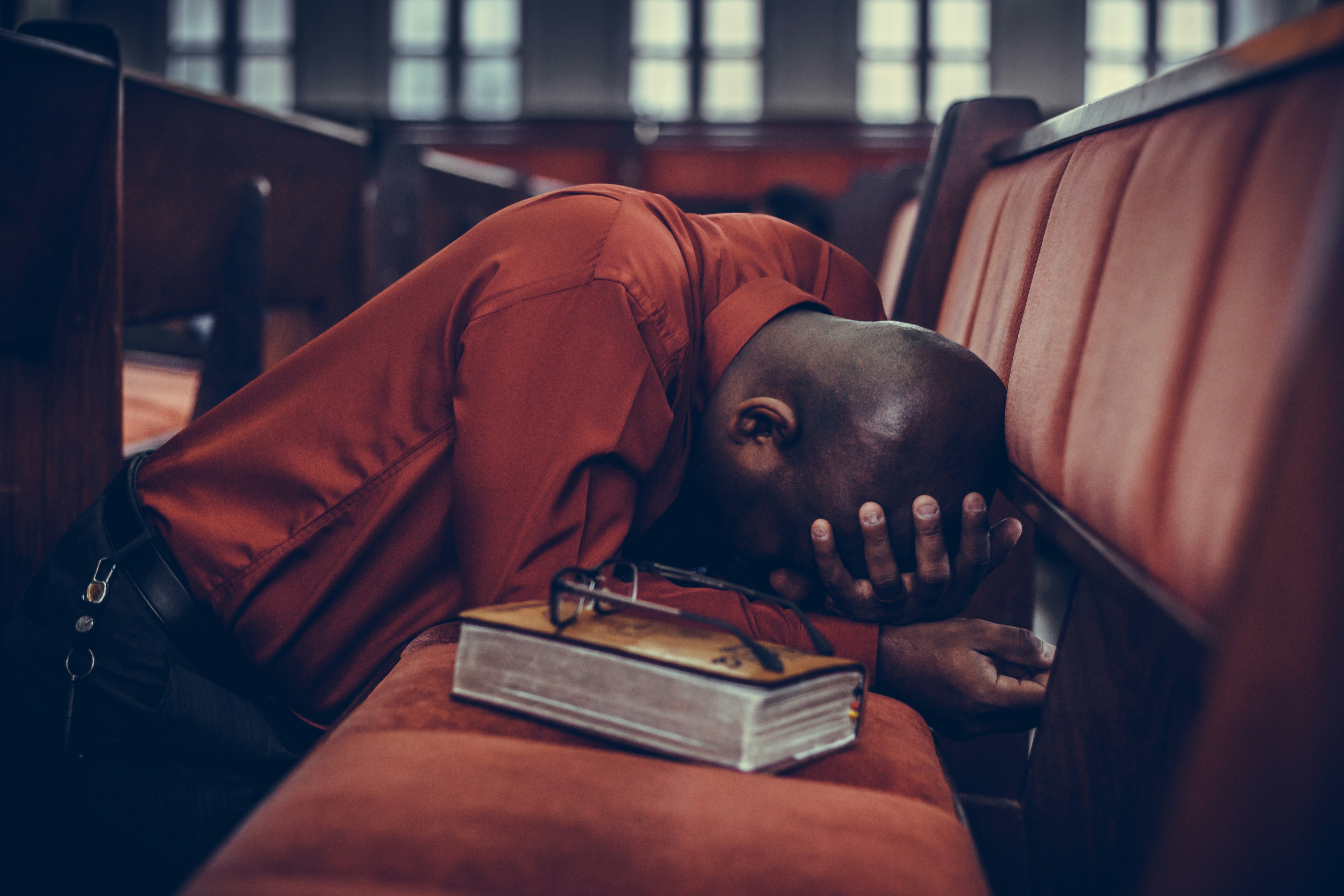 Man in pew praying on hands and knees